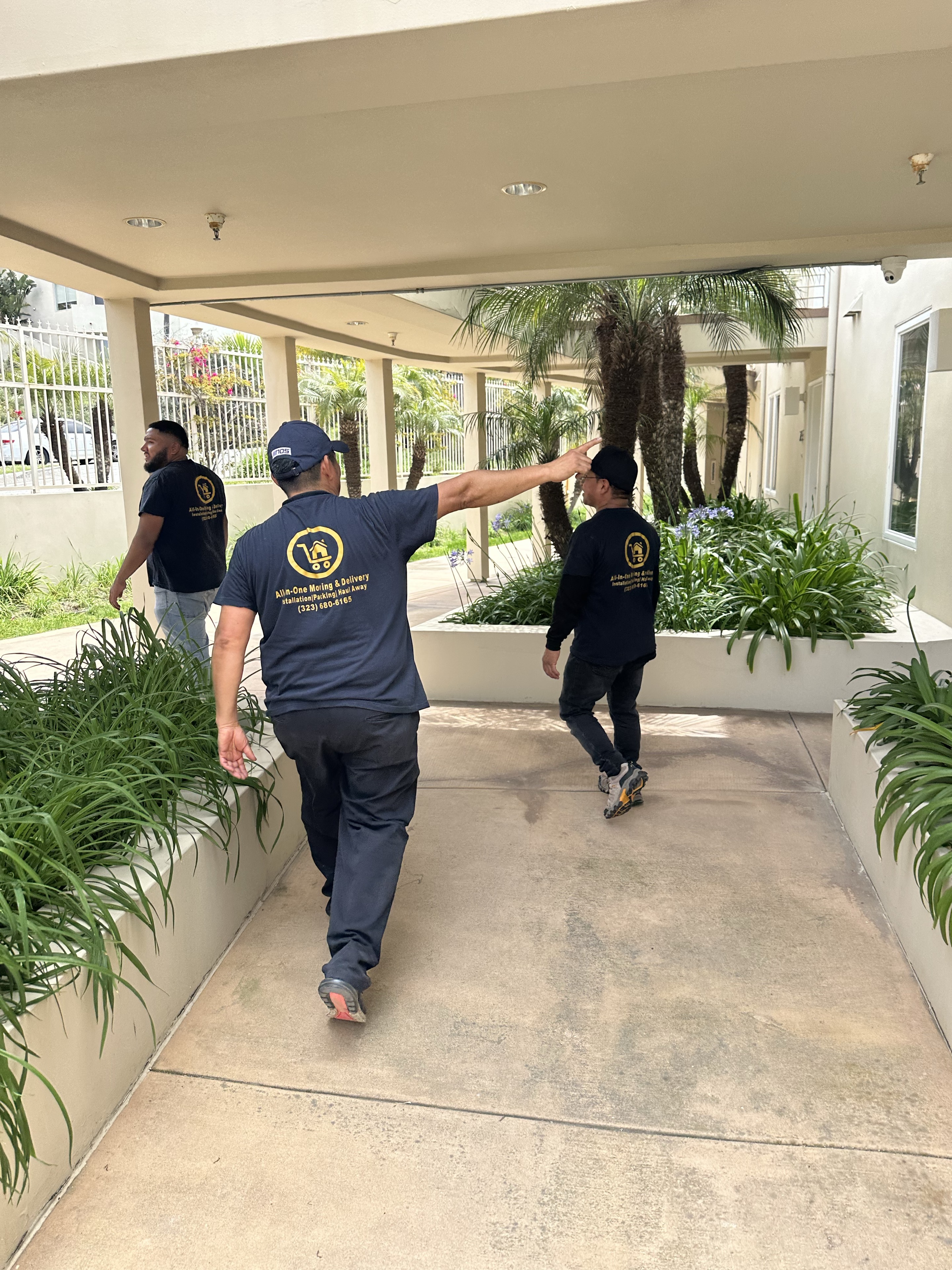 Three crew members walking through an apartment courtyard in All In One uniforms