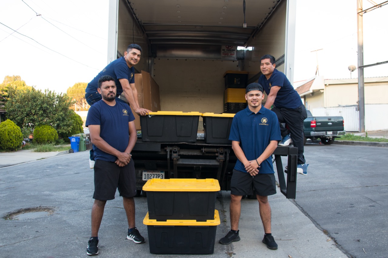 All In One crew beside an open truck with packed moving totes